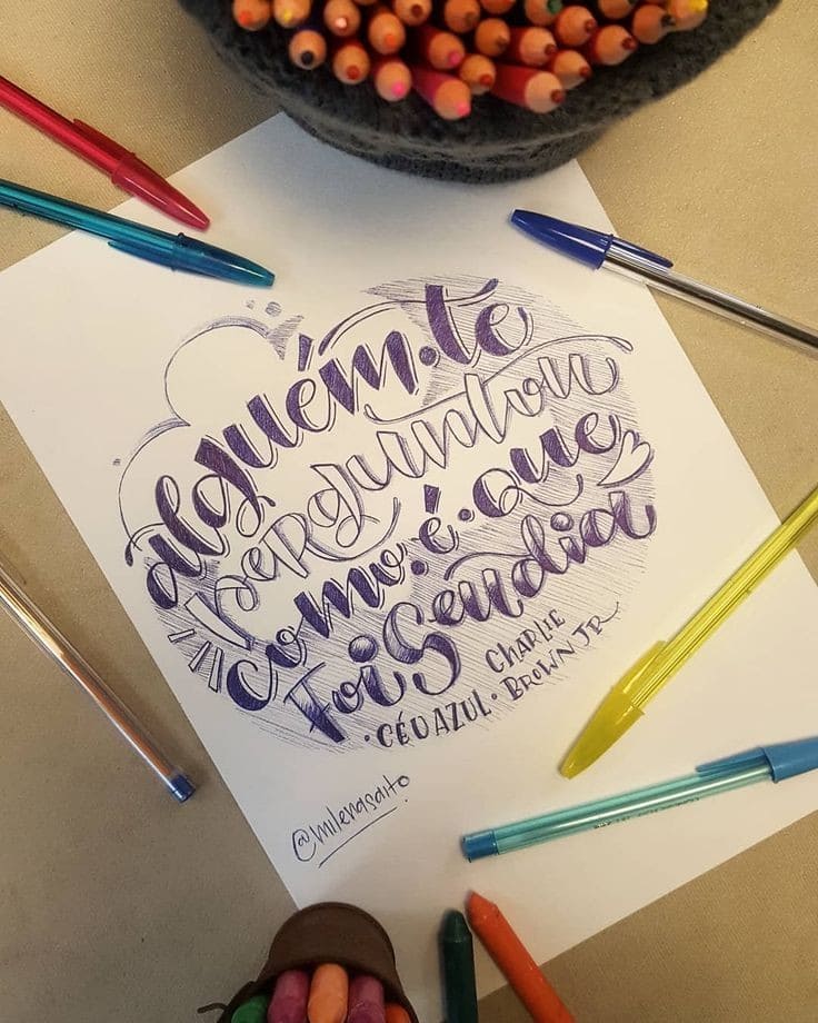 lettering com caneta esferográfica azul e algumas canetas posicionadas em cima