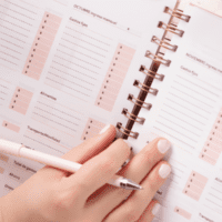pessoa segurando uma caneta e caderno de planejamento